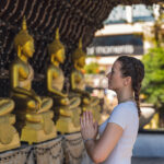 A girl worshipping the golden statues at Gangaramaya, revealing the beauty of the Culture and Traditions in Sri Lanka