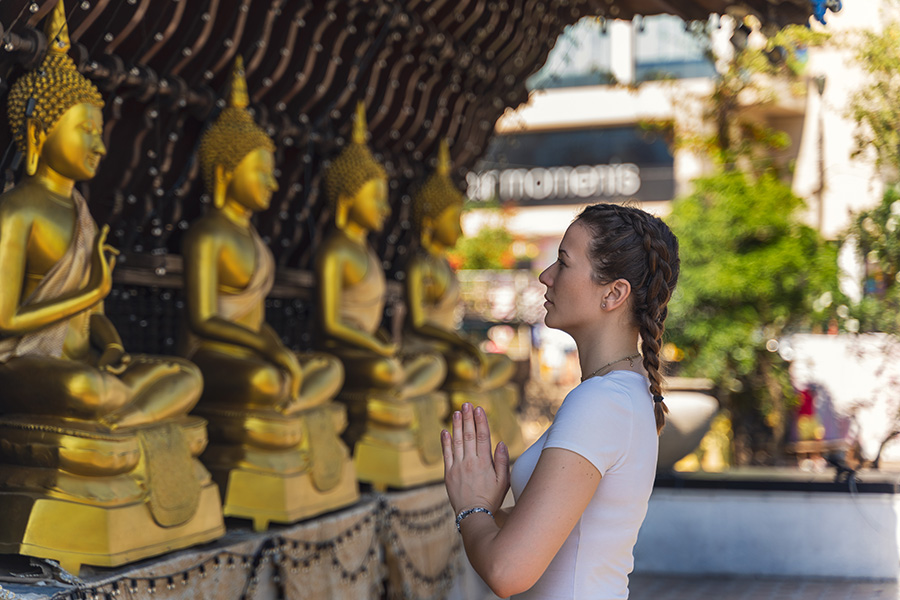 A girl worshipping the golden statues at Gangaramaya, revealing the beauty of the Culture and Traditions in Sri Lanka