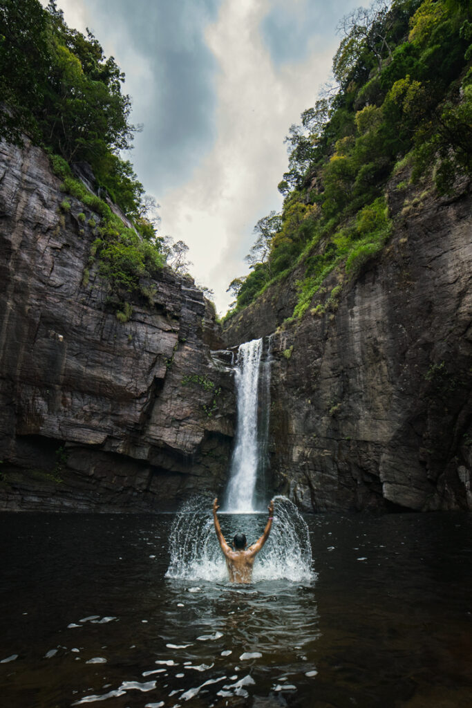A man enjoying himself amidst the waters of Dumbara Waterfall in Sri Lanka