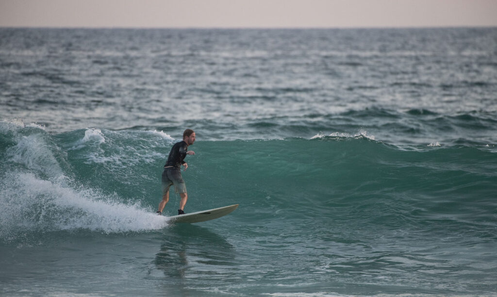 A tourist in Black shorts surfing on Sri Lankan waves