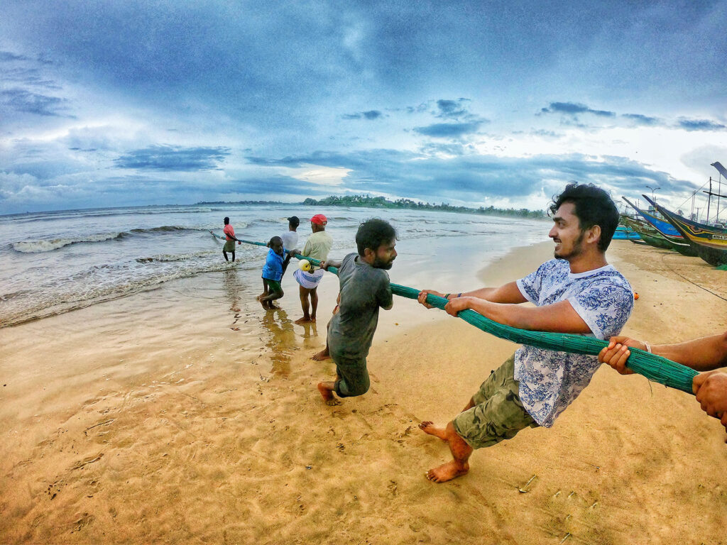 Men pulling the seine fishing net on the Galle beach in Sri Lanka