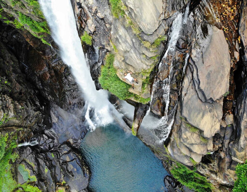 The sky view of the Lakshapana waterfall pouring water over the rocky terrains