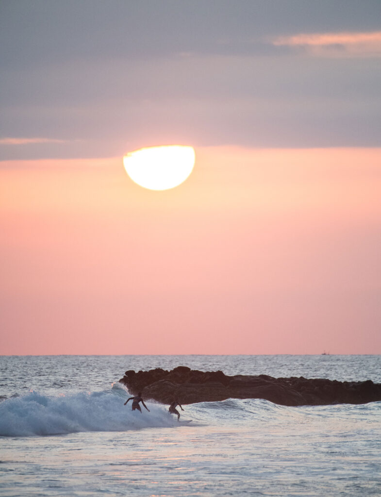 Two men surfing on the waves in Weligama Sri Lanka, in an evening