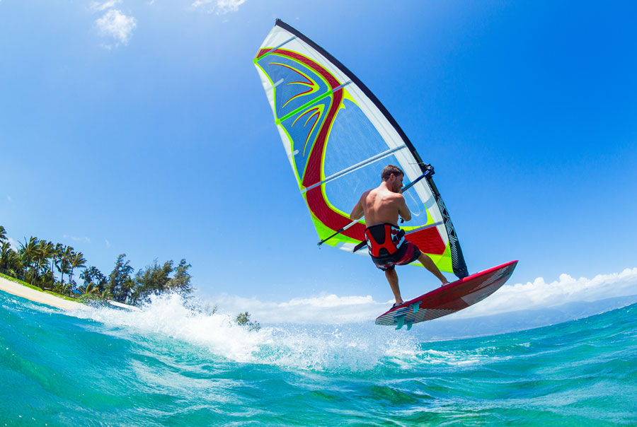 A foreign boy windsurfing on the waves, enjoying one of the most exciting water sports in Sri Lanka