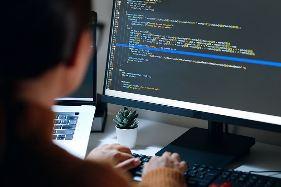 A woman coding on a computer, a part of an AI software